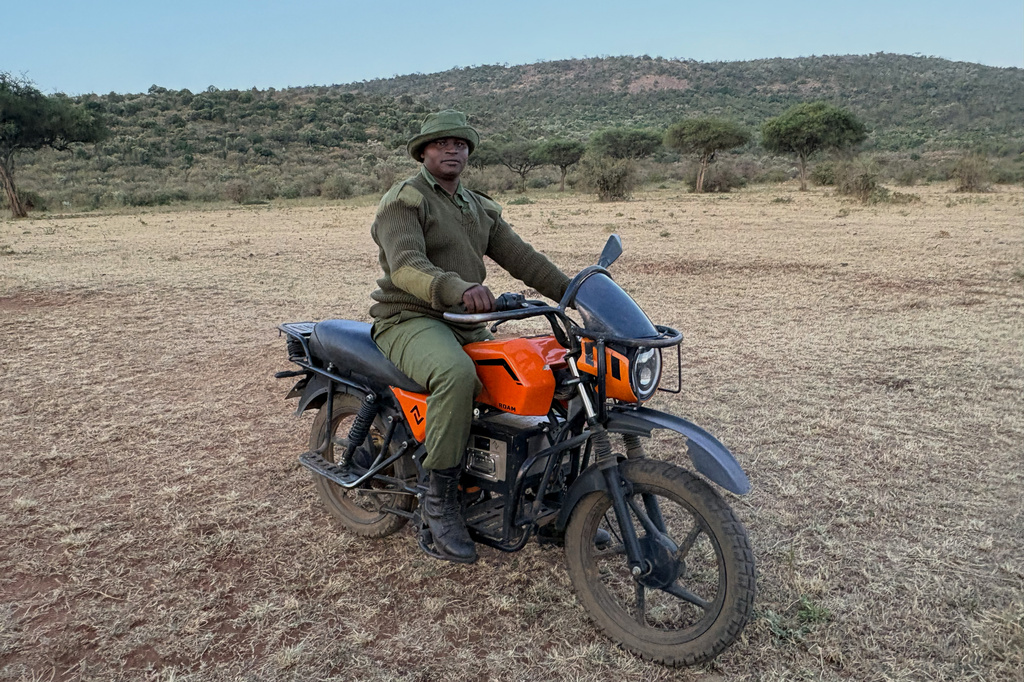 In this photo taken with a smartphone, Mara Siena ranger Joshua Kijape stands beside his electric motorcycle, which he uses while patrolling the Maasai Mara, Kenya, Saturday, Aug. 29, 2026. (AP Photo/Allan Olingo)