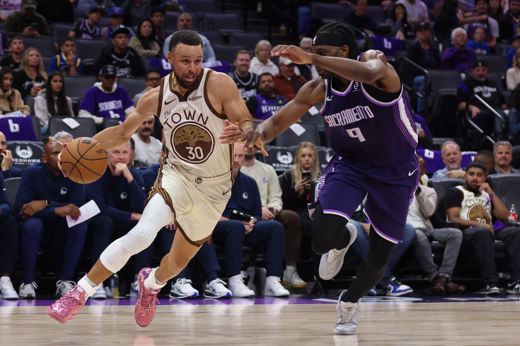 Golden State Warriors guard Stephen Curry (30) dribbles the ball past Sacramento Kings forward Precious Achiuwa (9) during the second half of an NBA basketball game against the Sacramento Kings,Friday, April 10, 2026, in Sacramento, Calif. (AP Photo/Scott Marshall)