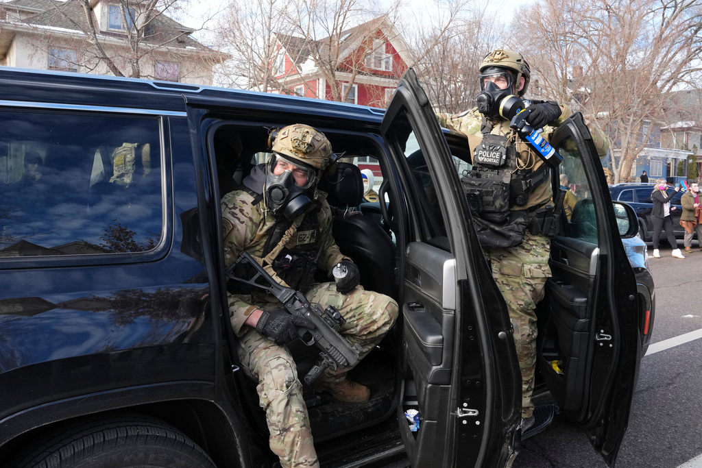 Federal agents get ready to disperse tear gas into a crowd at a protest, Monday, Jan. 12, 2026 in Minneapolis (AP Photo/Adam Gray)
