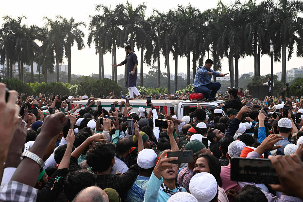 People gather around an ambulance carrying the body of leading Bangladeshi activist Sharif Osman Hadi, who died from gunshot wounds sustained in an attack in Dhaka earlier this month, following his funeral prayers outside the nation's Parliament complex in Dhaka, Bangladesh, Saturday, Dec. 20, 2025. (AP Photo/Mahmud Hossain Opu)