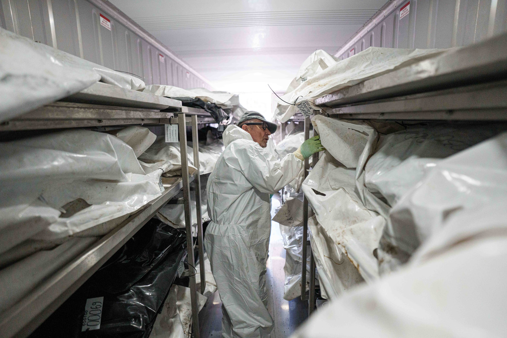A morgue worker searches for a body of Ukrainian soldier before examination at the forensic bureau in Kyiv region, Ukraine, on Monday, June 1, 2026. (AP Photo/Evgeniy Maloletka)