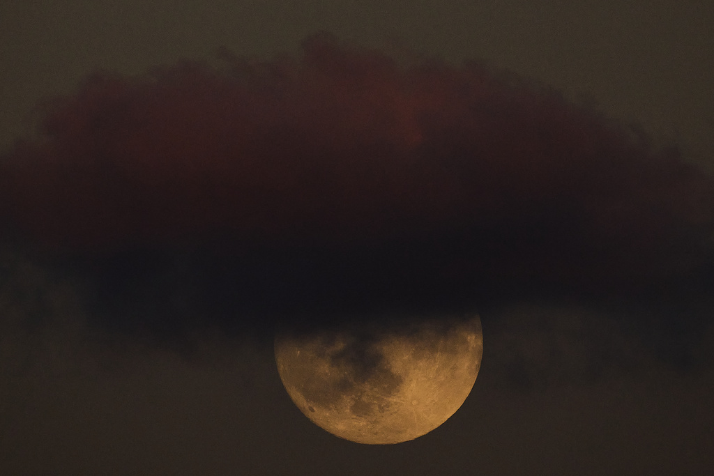 The full Harvest Moon rises behind a cloud in the sky in Hadera, Israel, Monday, Oct. 6, 2025. (AP Photo/Ariel Schalit)