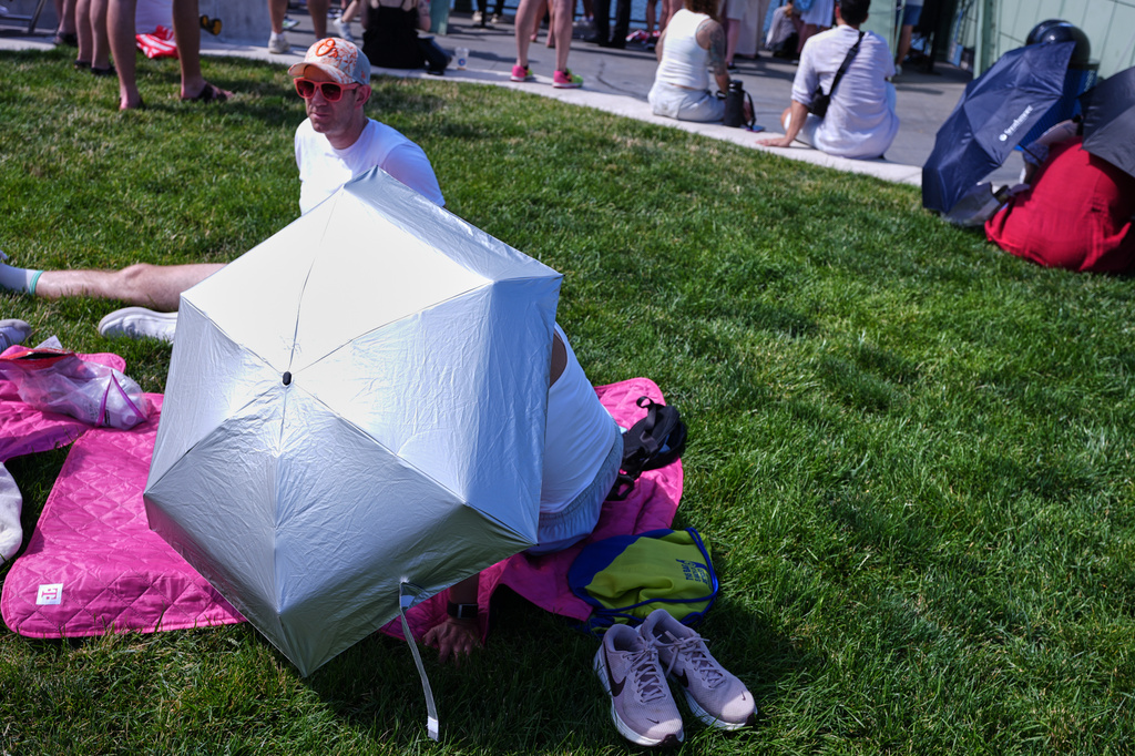 A person shields themselves from the sun at Pier 57 during a heat wave ahead of the International Parade of Sail, Saturday, July 4, 2026, in New York. (AP Photo/Sydney Schaefer)