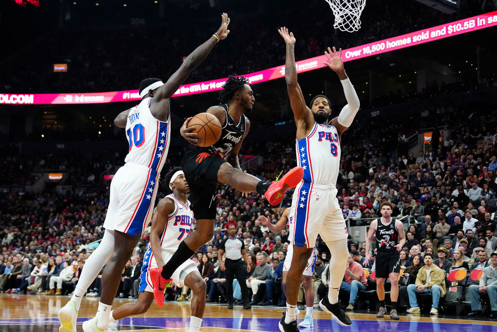 Toronto Raptors guard Immanuel Quickley (5) makes a pass under pressure from Philadelphia 76ers forward Adem Bona (30) and teammate Paul George (8) during first half NBA basketball action in Toronto, Monday, Jan. 12, 2026. (Frank Gunn/The Canadian Press via AP)