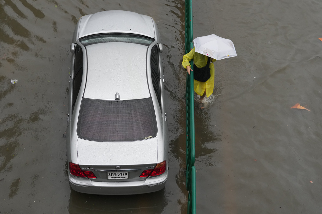 A woman wades through floodwaters after heavy rain in Bangkok, Thailand Saturday, Sept. 26, 2026. (AP Photo/Sakchai Lalit)