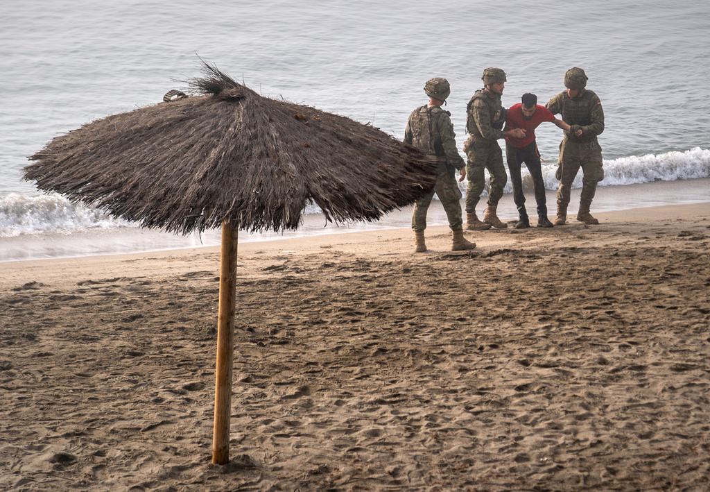 Spanish army soldiers assist a migrant who swam from Morocco to the Spanish enclave of Ceuta, Saturday, Aug. 1, 2026. (AP Photo/Antonio Sempere)