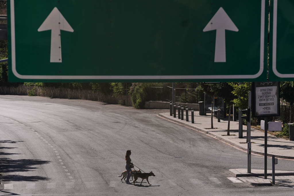 A woman walks with her dogs as they cross an empty street during the Jewish holiday of Yom Kippur, in Jerusalem, Monday, Sept. 21, 2026. (AP Photo/Mahmoud Illean)