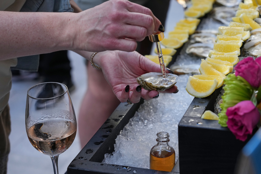 An event participant adds bitters to Alabama oysters during the South Beach Wine and Food Festival Friday, Feb. 20, 2026, in Miami Beach, Fla. (AP Photo/Marta Lavandier)
