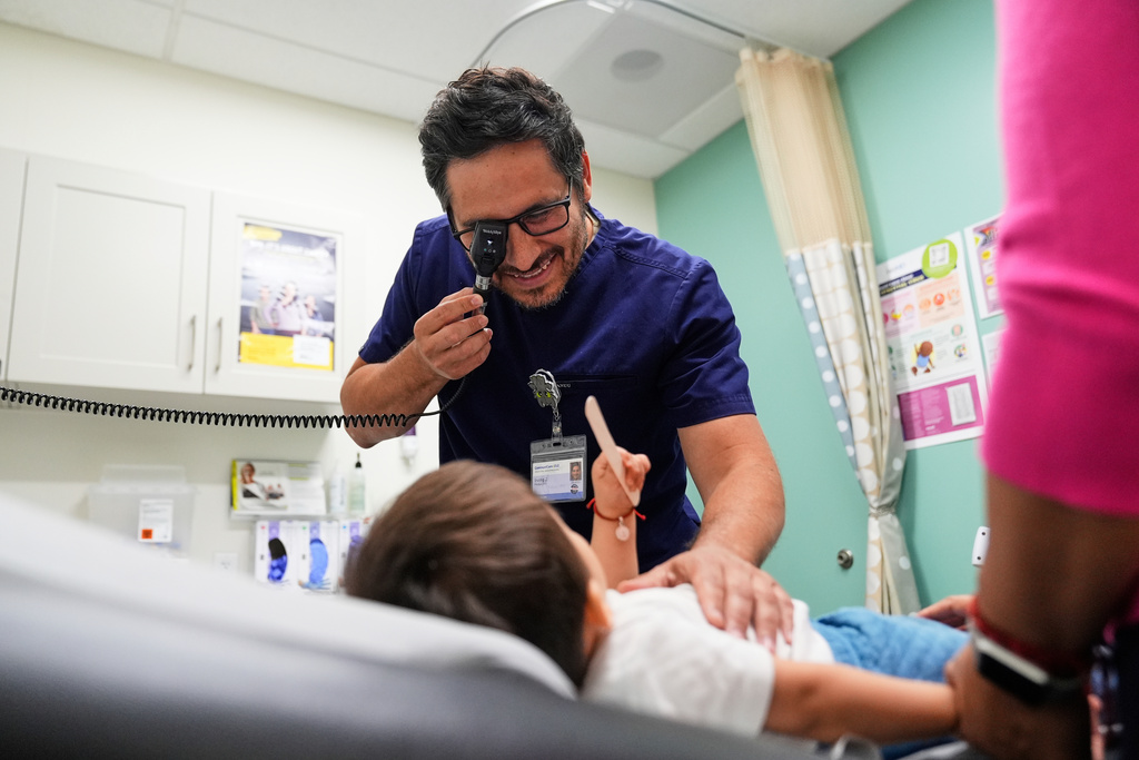 FILE - Pediatrician Irving Phillips, left, examines a 16-month-old boy at a CommuniCARE+OLE clinic, June 26, 2025, in Davis, Calif. (AP Photo/Godofredo A. Vásquez, File)