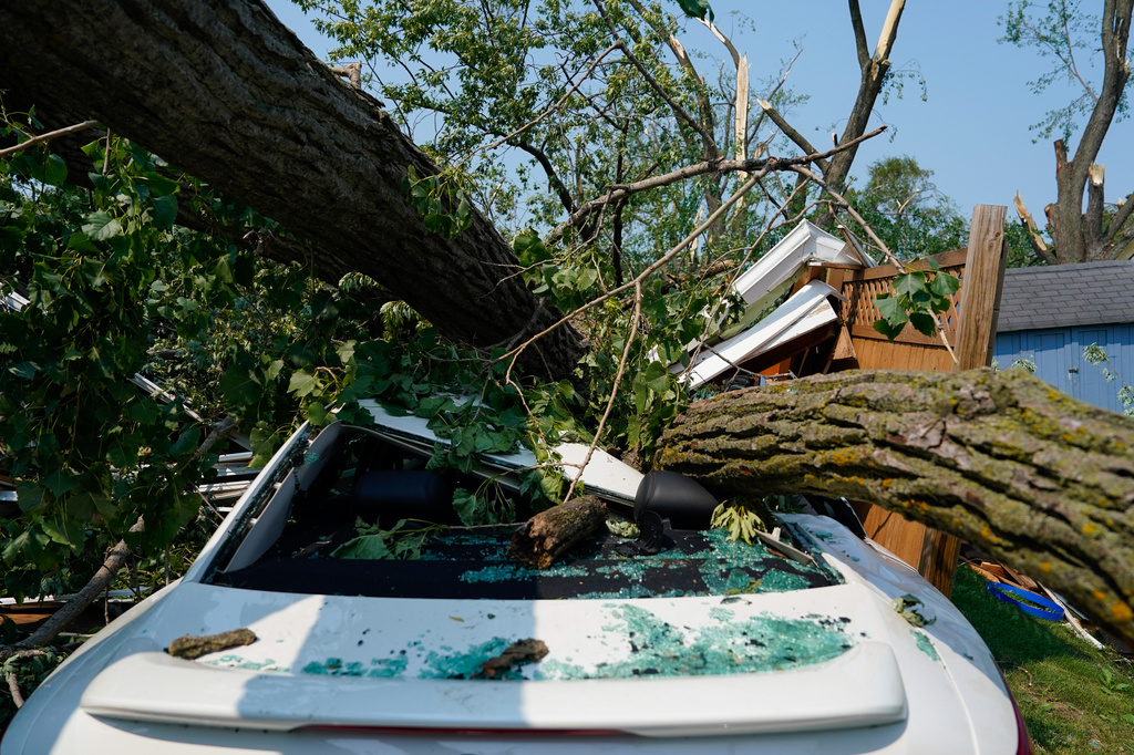 A car sits crushed beneath a fallen tree after a tornado tore through a day before in Appleton, Wis., Tuesday, July 28, 2026. (AP Photo/Kayla Wolf)