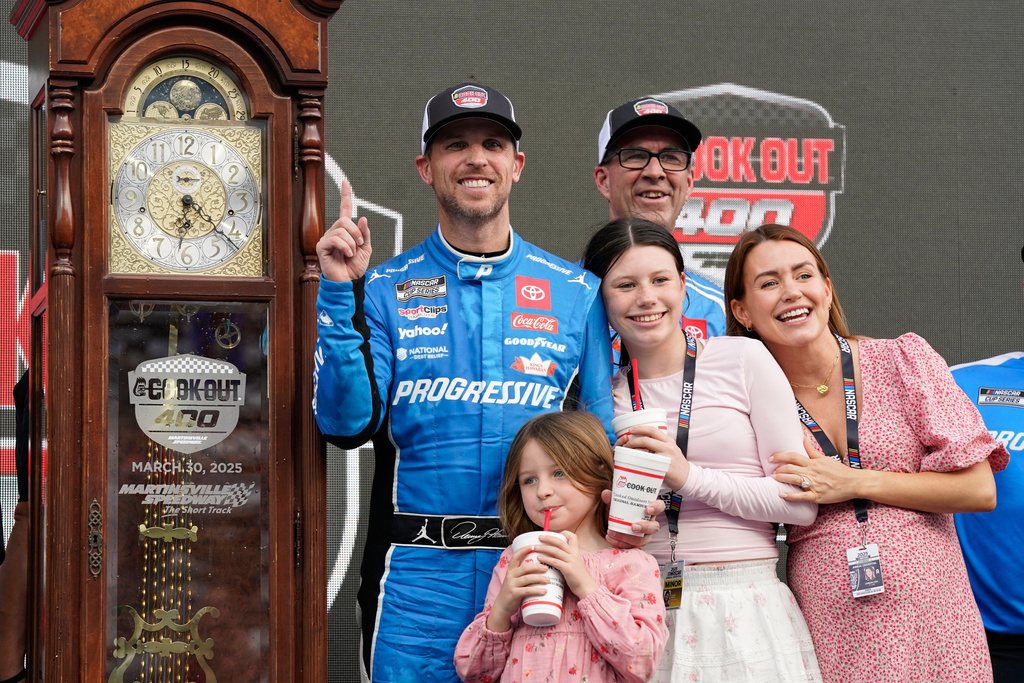 FILE - Denny Hamlin poses with the trophy in Victory Lane after winning a NASCAR Cup Series auto race in Martinsville, Va., March 30, 2025. (AP Photo/Chuck Burton, File)