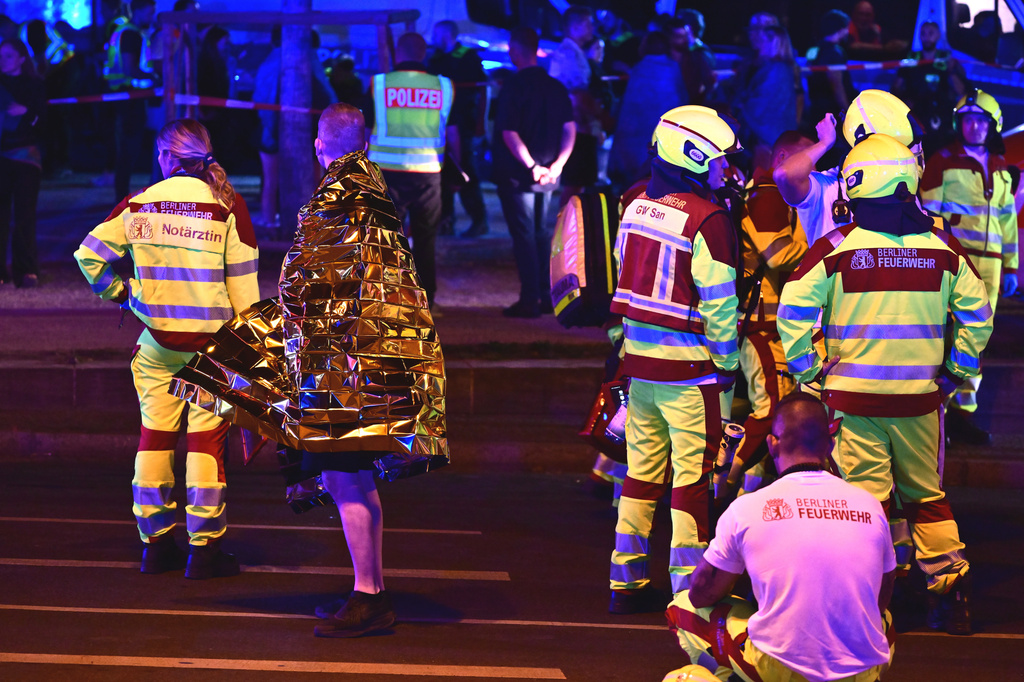 A person wrapped in a thermal blanket stands near emergency personnel following the cancellation of Christopher Street Day festivities in Berlin, on Saturday, July 25, 2026. (Fabian Sommer/dpa/dpa via AP)