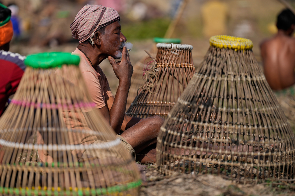 A villager smokes before participate in a community fishing as part of Bhogali Bihu celebrations which mark the end of the harvest season at Jalikhora village east of Guwahati, India, Tuesday, Jan. 13, 2026. (AP Photo/Anupam Nath)