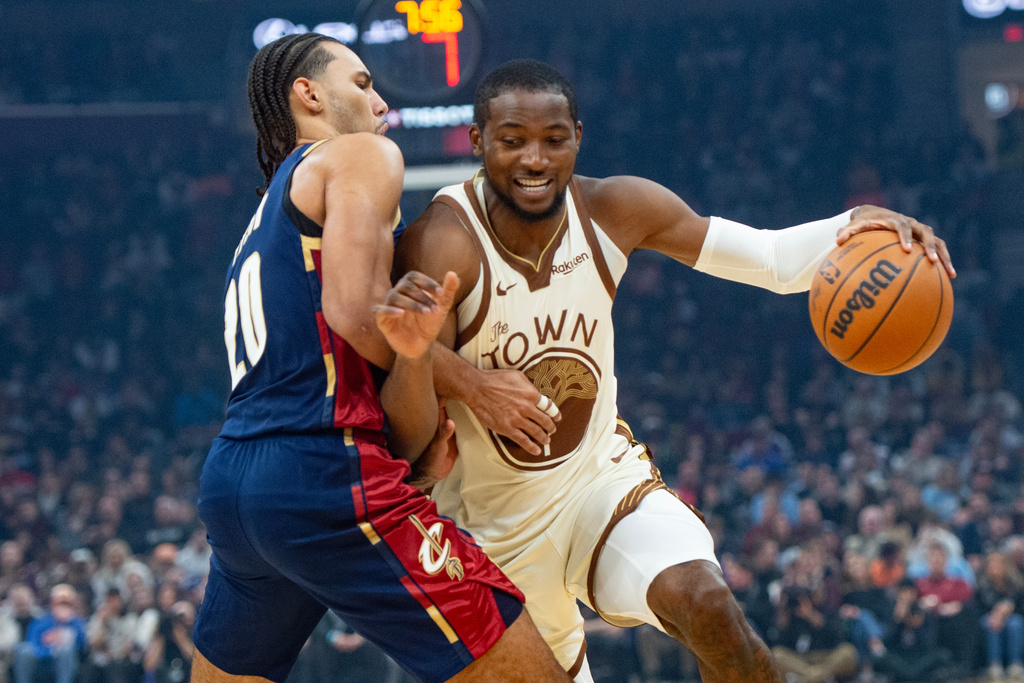 Golden State Warriors' Jonathan Kuminga, right, drives against Cleveland Cavaliers' Jaylon Tyson, during the first half of an NBA basketball game in Cleveland, Saturday, Dec. 6, 2025. (AP Photo/Phil Long)