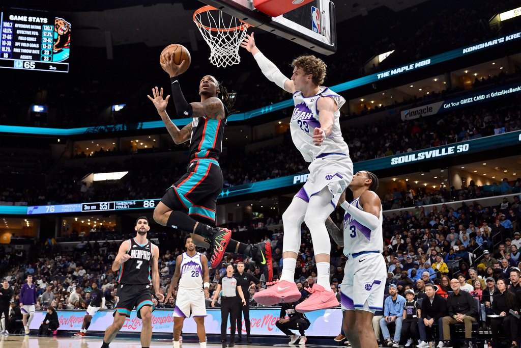 Memphis Grizzlies guard Ja Morant, top left, shoots ahead of Utah Jazz forward Lauri Markkanen (23) in the second half of an NBA basketball game Friday, Dec. 12, 2025, in Memphis, Tenn. (AP Photo/Brandon Dill)
