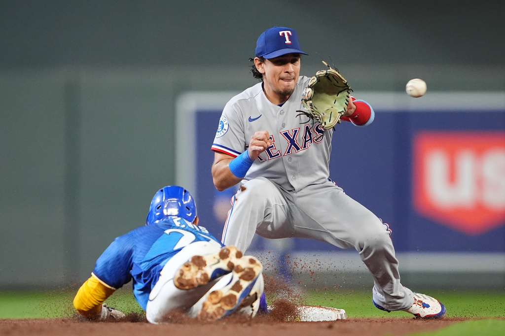 Texas Rangers second baseman Nicky Lopez, right, waits to make a catch while Minnesota Twins' Royce Lewis, left, slides safely into second on a steal during the second inning of a baseball game, Friday, Sept. 25, 2026, in Minneapolis. (AP Photo/Ellen Schmidt)