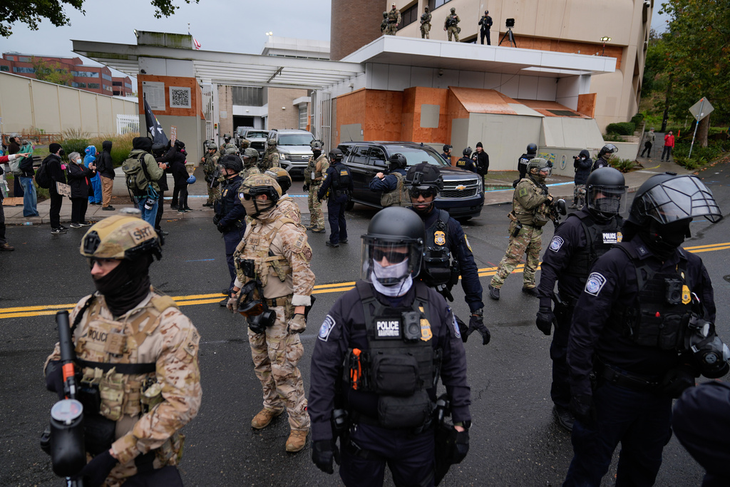 Law enforcement stand in the street to allow vehicles to leave a U.S. Immigration and Customs Enforcement facility during a protest on Saturday, Oct. 11, 2025, in Portland, Ore. (AP Photo/Jenny Kane)