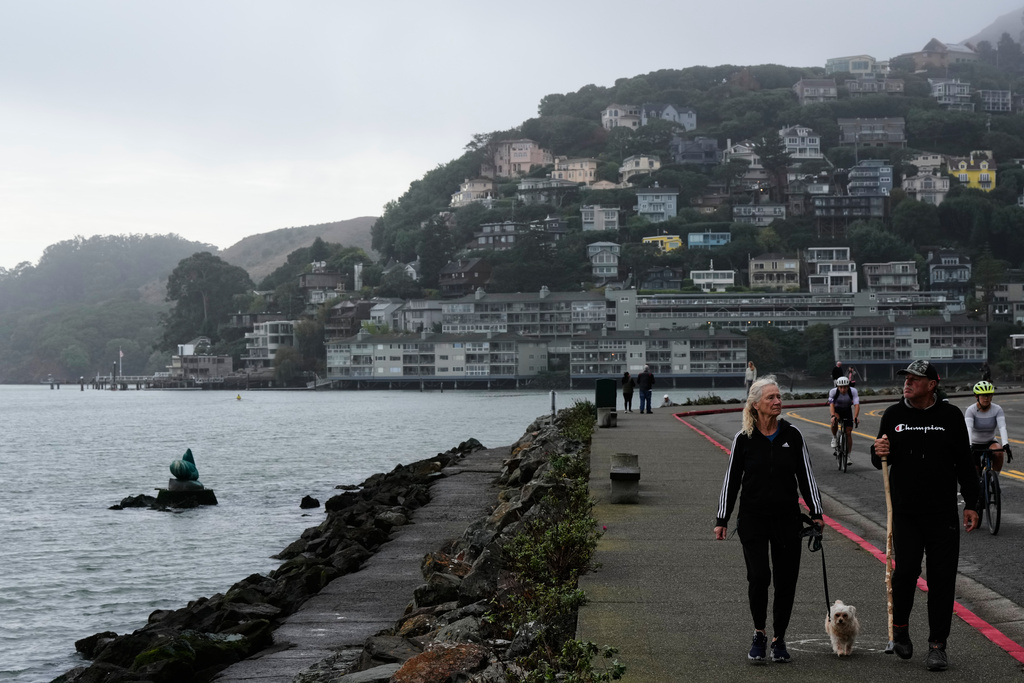 People walk on a sidewalk next to the San Francisco Bay in Sausalito, Calif., Sunday, Oct. 26, 2025. (AP Photo/Godofredo A. Vásquez)