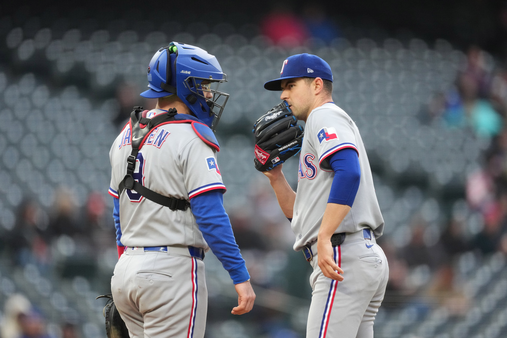 Texas Rangers catcher Danny Jansen, left, confers with starting pitcher MacKenzie Gore, right, after Gore loaded the bases in the first inning of a baseball game against the Colorado Rockies, Monday, May 18, 2026, in Denver. (AP Photo/David Zalubowski)