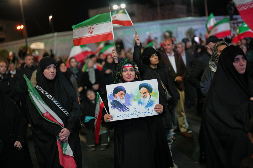 A woman holds a poster depicting the late Iran’s Supreme Leader Ayatollah Ali Khamenei, left, and the late revolutionary founder Ayatollah Ruhollah Khomeini during a pro-government gathering in a square in Tehran, Iran, Sunday, April 5, 2026. (AP Photo/Francisco Seco)