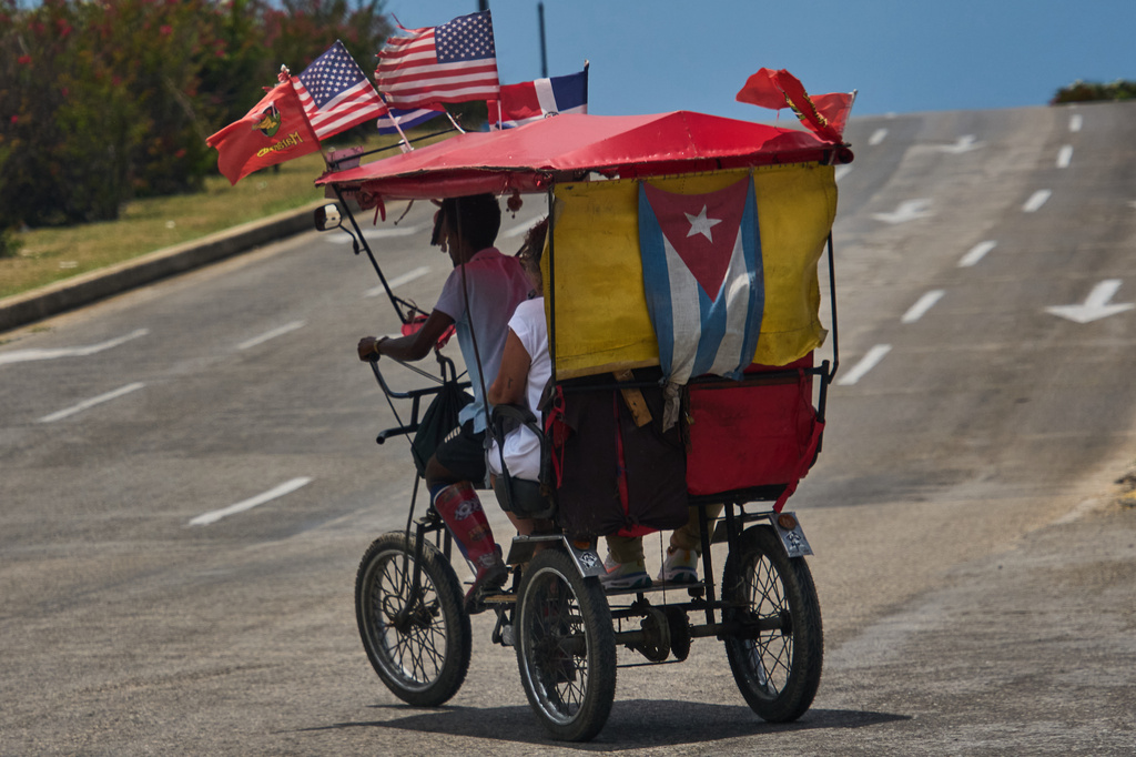 Passengers ride in a bicycle taxi adorned with the national flags representing the U.S., Cuba and the Dominican Republic, in Havana, Cuba, Wednesday, May 20, 2026. (AP Photo/Ramon Espinosa)