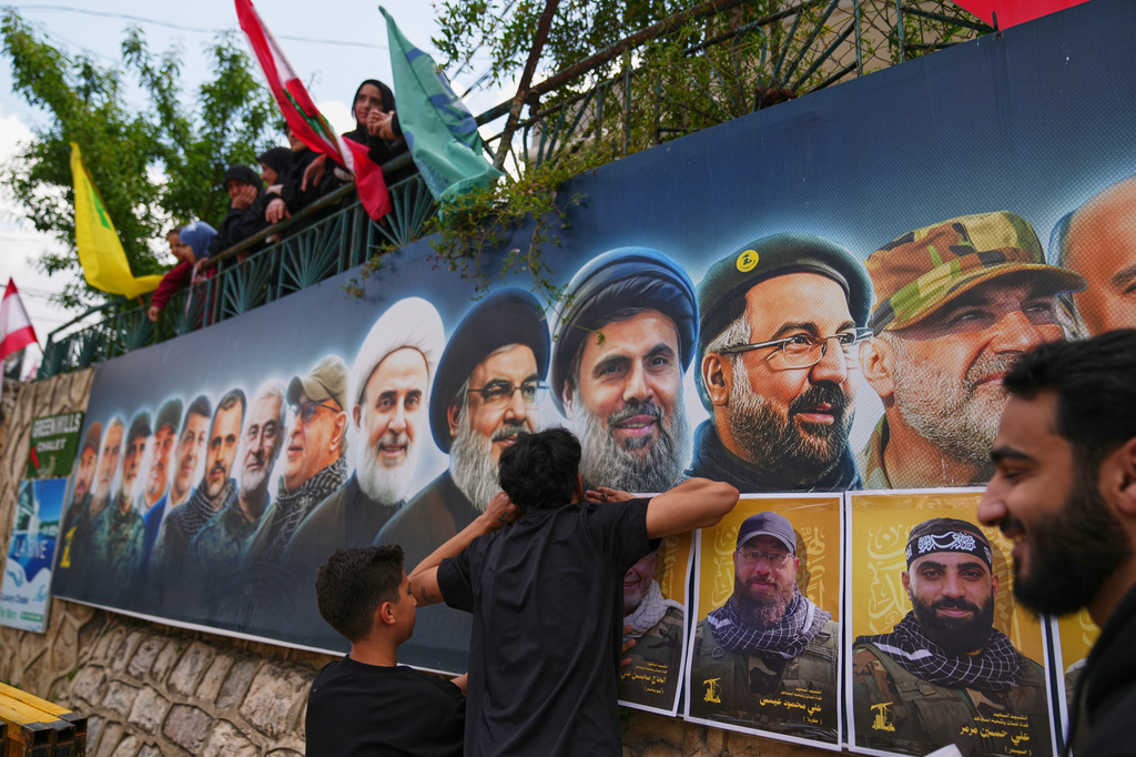 Hezbollah supporters hang portraits of Hezbollah fighters killed in Israeli airstrikes during their funeral procession in the southern village of Kfar Sir, Lebanon, Tuesday, April 21, 2026. (AP Photo/Hassan Ammar)