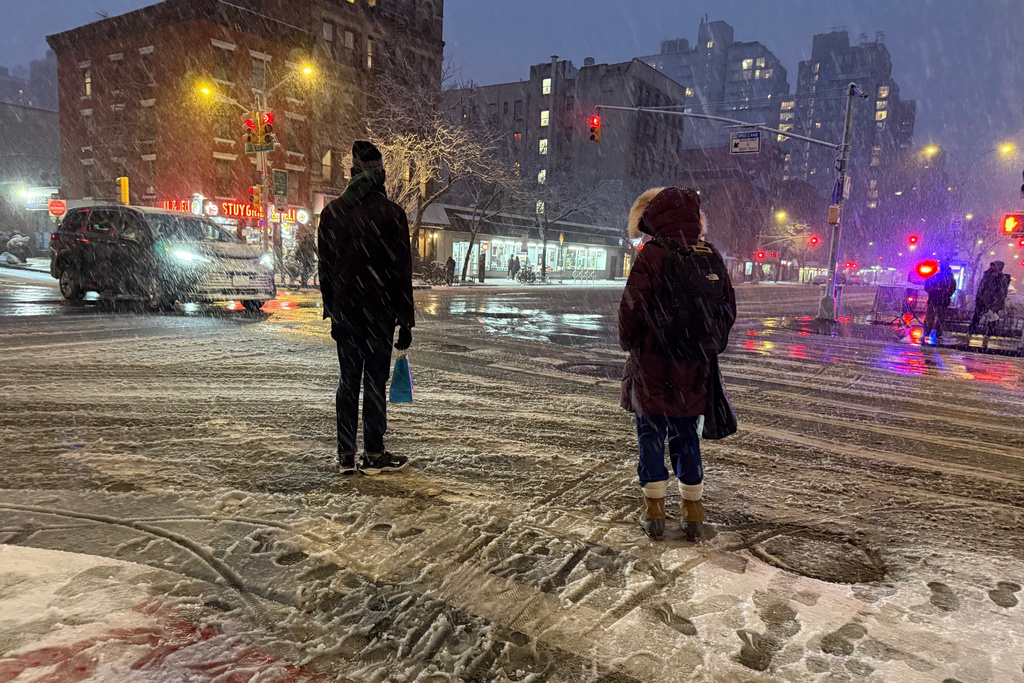 People wait to cross the corner of 20th Street and First Ave. during a snowstorm, Sunday, Feb. 22, 2026, in New York. (AP Photo/Pamela Hassell)