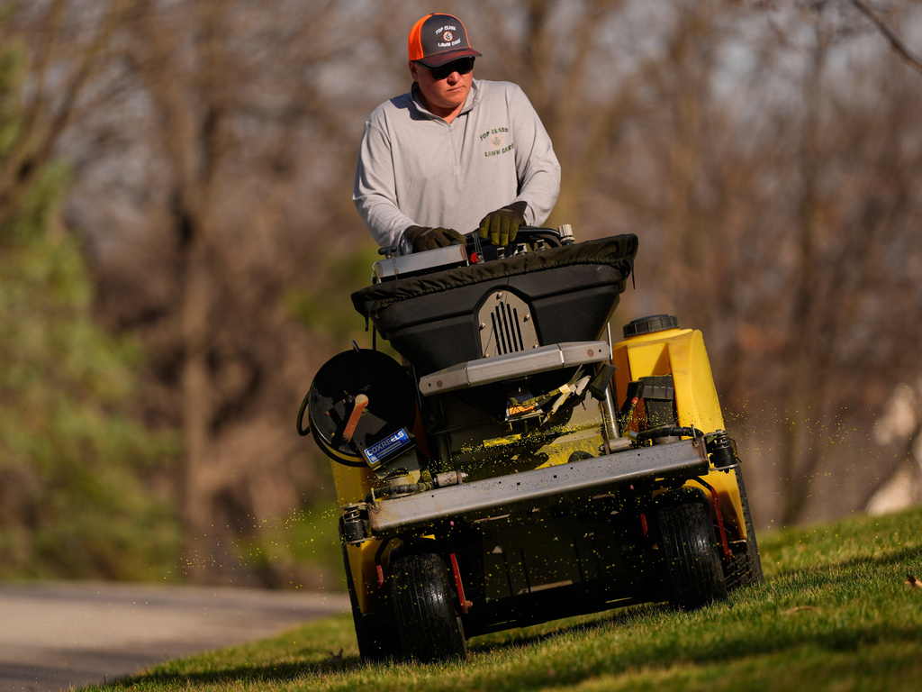 Top Class Lawn Care owner Jake Wilson fertilizes a lawn Thursday, March 26, 2026, in Kansas City, Mo. (AP Photo/Charlie Riedel)