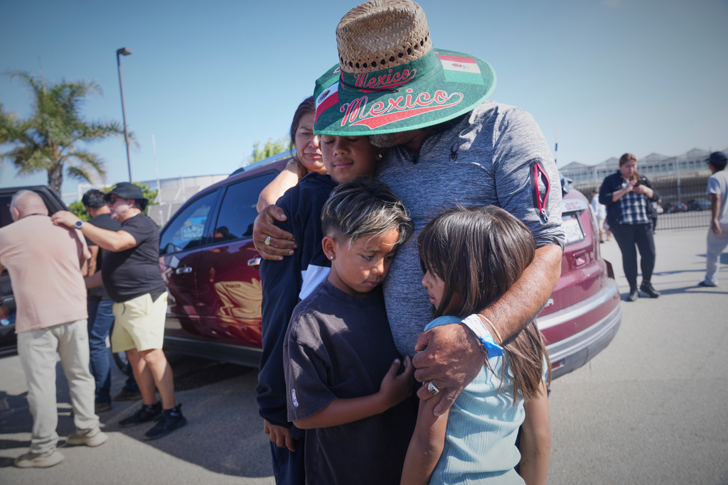 FILE - People embrace outside of Glass House Farms, a day after an immigration raid on the facility, on July 11, 2025, in Camarillo, Calif. (AP Photo/Damian Dovarganes, File)