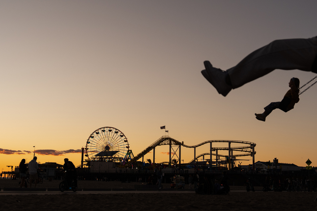 Children swing in silhouette near the Santa Monica Pier, which displays the "End of the Trail" Route 66 sign in Santa Monica, Calif., Nov. 22, 2025. (AP Photo/Jae C. Hong)