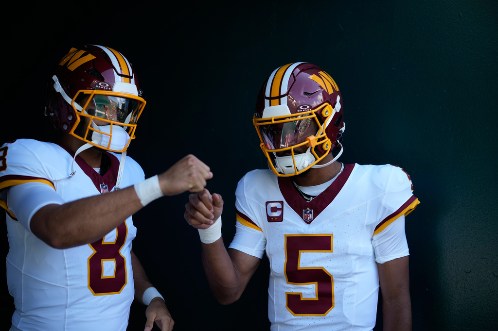 Washington Commanders quarterback Marcus Mariota (8) and quarterback Jayden Daniels (5) prepare for an NFL football game against the Philadelphia Eagles, Sunday, Sept. 13, 2026, in Philadelphia. (AP Photo/Matt Slocum)