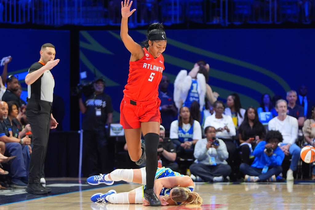 Atlanta Dream forward Angel Reese (5) jumps over a fallen Dallas Wings guard Paige Bueckers during the first half of a WNBA basketball game in Arlington, Texas, Tuesday, May 12, 2026. (AP Photo/LM Otero)