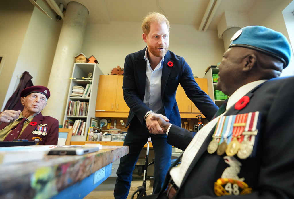 CORRECTS NAME FROM OSSIE TO OZZIE - Prince Harry, center, shakes hands with war veteran Ozzie Reece as he meets with some of Canada's oldest veterans, joining them in a creative arts program at Sunnybrook Hospital's veterans center in Toronto, Thursday, Nov. 6, 2025. (Nathan Denette /The Canadian Press via AP)