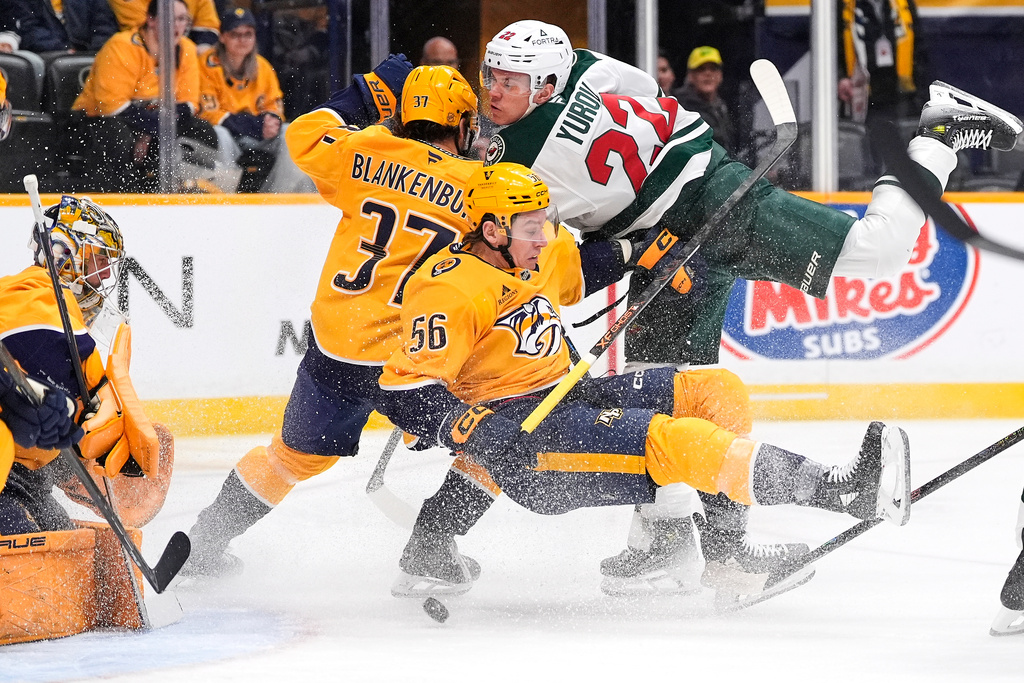 Minnesota Wild right wing Danila Yurov (22) tries to get the puck past Nashville Predators left wing Erik Haula (56), defenseman Nick Blankenburg (37) and goaltender Juuse Saros, left, during the first period of an NHL hockey game Wednesday, Feb. 4, 2026, in Nashville, Tenn. (AP Photo/George Walker IV)