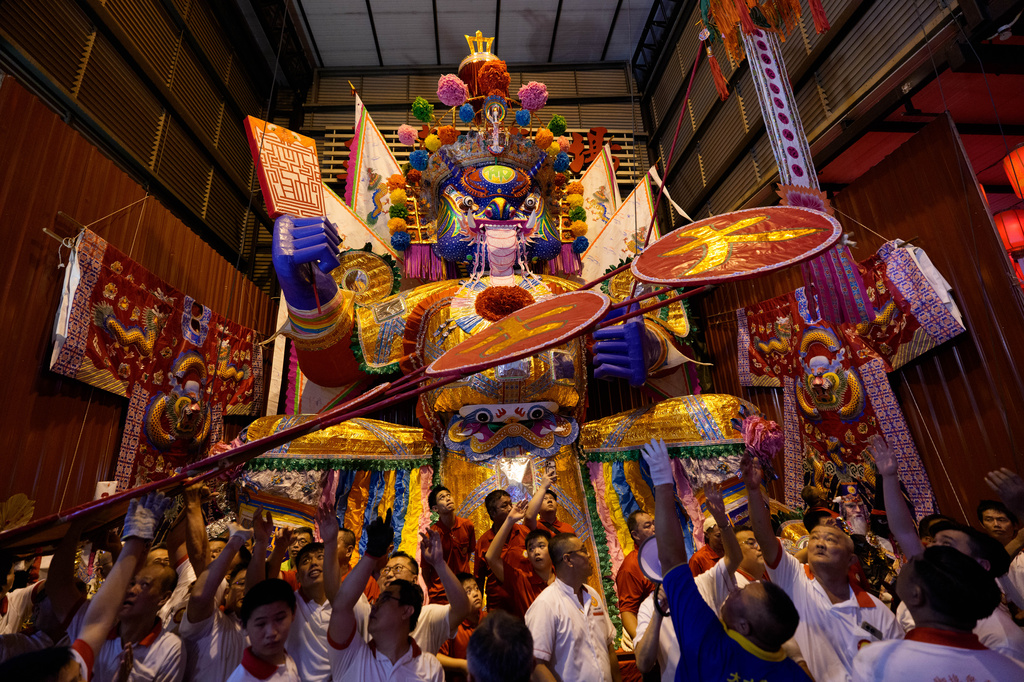 Participants take part in a ceremony in front of a paper statue of Da Shi Ye, the Guardian God of Ghosts, during the Hungry Ghost Festival in Bukit Metajam, Malaysia, Saturday, Aug. 29, 2026. (AP Photo/Vincent Thian)