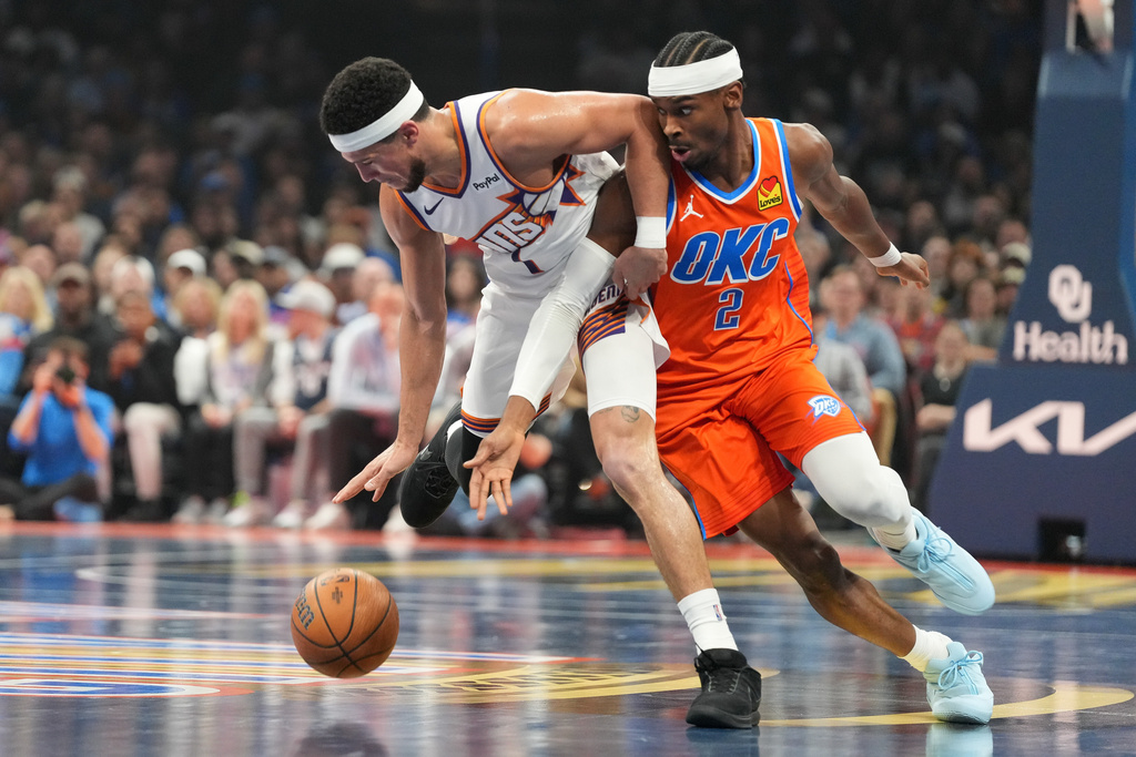 Oklahoma City Thunder guard Shai Gilgeous-Alexander, right, tries to steal the ball from Phoenix Suns guard Devin Booker during the first half of an NBA Cup basketball game, Friday, Nov. 28, 2025, in Oklahoma City. (AP Photo/Kyle Phillips)
