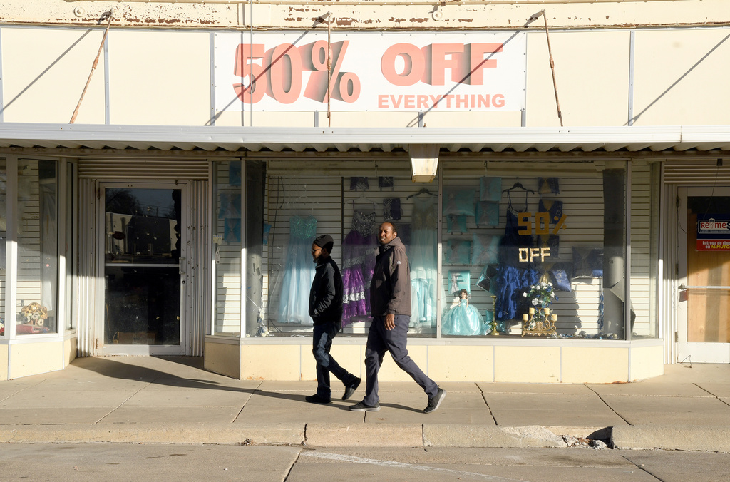 Two men walk past a business in downtown Lexington, Neb., Saturday, Dec. 6, 2025. (AP Photo/Thomas Peipert)