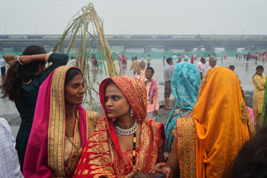 Women wait to perform prayers during Chhath festival on the banks of the river Yamuna, in New Delhi, India, Monday, Oct. 27, 2025. (AP Photo/Manish Swarup)