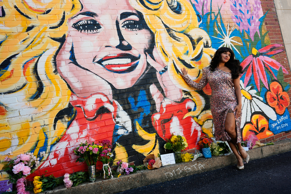 Sunny Holiday poses for a photo near a mural of Dolly Parton on Tuesday, Aug. 25, 2026, in Nashville, Tenn. (AP Photo/George Walker IV)