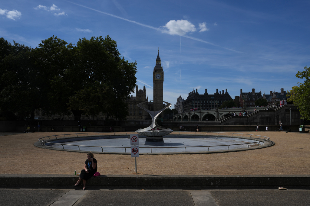 A woman sits in front of the Houses of Parliament in London, Monday, Aug. 10, 2026. (AP Photo/Kin Cheung)
