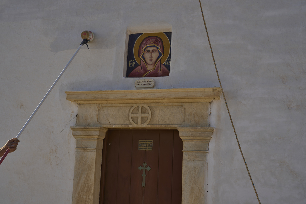 Naim Domi, 50, an Albanian worker who has lived in Greece for 17 years, paints the Panagia Faneromeni co-family-owned chapel, near the village of Pyrgos, on the island of Tinos, Greece, Sunday, Sept. 7, 2025. (AP Photo/Petros Giannakouris)