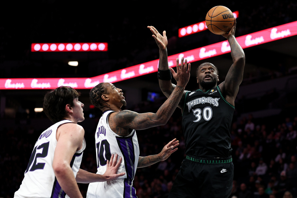 Minnesota Timberwolves forward Julius Randle, right, goes up for a shot as Sacramento Kings guard Demar Derozan, middle, defends during the first half of an NBA basketball game Sunday, Dec. 14, 2025, in Minneapolis. (AP Photo/Matt Krohn)