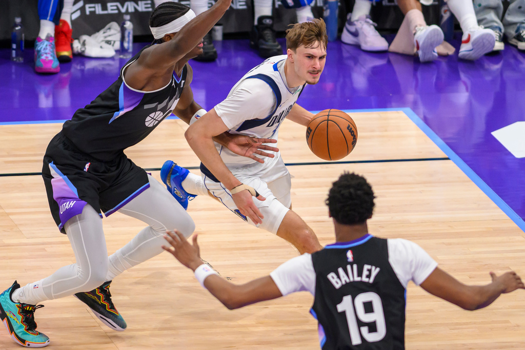 Dallas Mavericks forward Cooper Flagg, center, drives to the basket guarded by Utah Jazz forward Taylor Hendricks, left, during the first half of an NBA basketball game, Monday, Dec. 15, 2025, in Salt Lake City. (AP Photo/Tyler Tate)