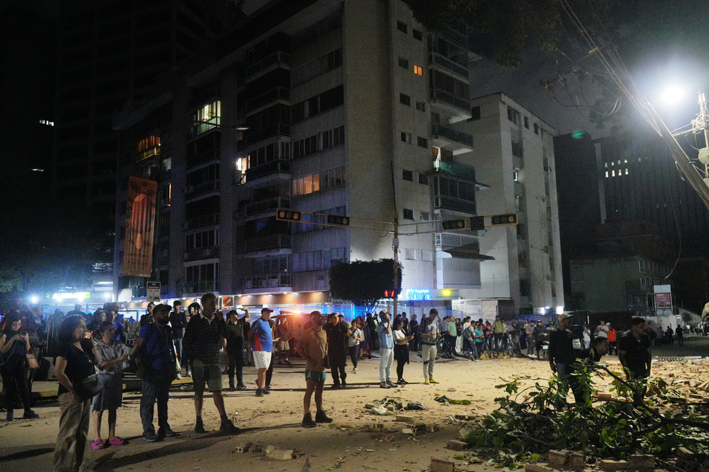 People stand outside damaged buildings after an earthquake in Caracas, Venezuela, Wednesday, June 24, 2026. (AP Photo/Adrian Naranjo)