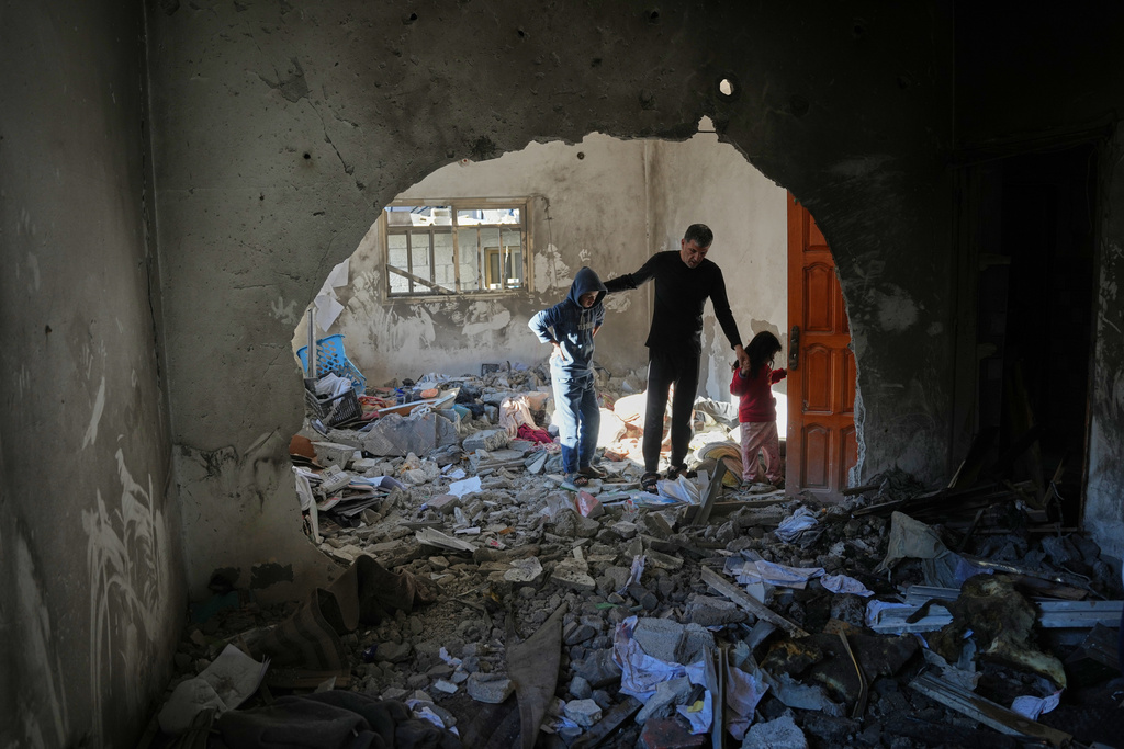 Palestinians inspect the rubble of the al-Hawli family home, destroyed in an Israeli strike in Deir al-Balah, in the central Gaza Strip, Friday, Jan. 16, 2026. (AP Photo/Abdel Kareem Hana)