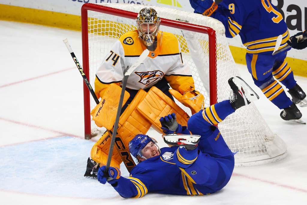 Buffalo Sabres defenseman Bowen Byram (4) falls in front of Nashville Predators goaltender Juuse Saros (74) during the third period of an NHL hockey game Saturday, March 7, 2026, in Buffalo, N.Y. (AP Photo/Jeffrey T. Barnes)