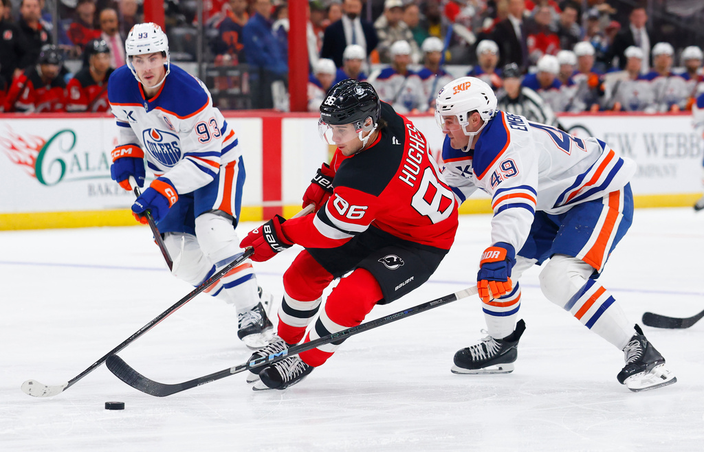 CORRECTS YEAR TO 2025, NOT 2024 - New Jersey Devils center Jack Hughes (86) plays the puck against Edmonton Oilers defenseman Ty Emberson (49) and center Ryan Nugent-Hopkins (93) during the second period of an NHL hockey game, Saturday, Oct. 18, 2025, in Newark, N.J. (AP Photo/Noah K. Murray)