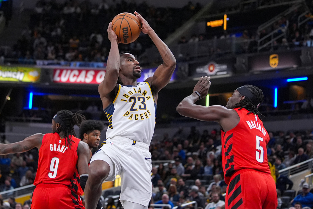 Indiana Pacers guard Aaron Nesmith (23) shoots over Portland Trail Blazers guard Jrue Holiday (5) during the first half of an NBA basketball game in Indianapolis, Wednesday, March 18, 2026. (AP Photo/Michael Conroy)