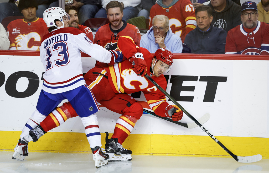 Montreal Canadiens' Cole Caufield, left, checks Calgary Flames' Mikael Backlund during second period NHL hockey action in Calgary on Wednesday, Oct. 22, 2025. (Jeff McIntosh/The Canadian Press via AP)
