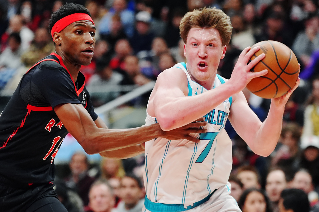 Charlotte Hornets' Kon Knueppel (7) drives past Toronto Raptors' Ja'Kobe Walter (14) during first half NBA basketball action in Toronto on Friday, Dec. 5, 2025. (Frank Gunn/The Canadian Press via AP)